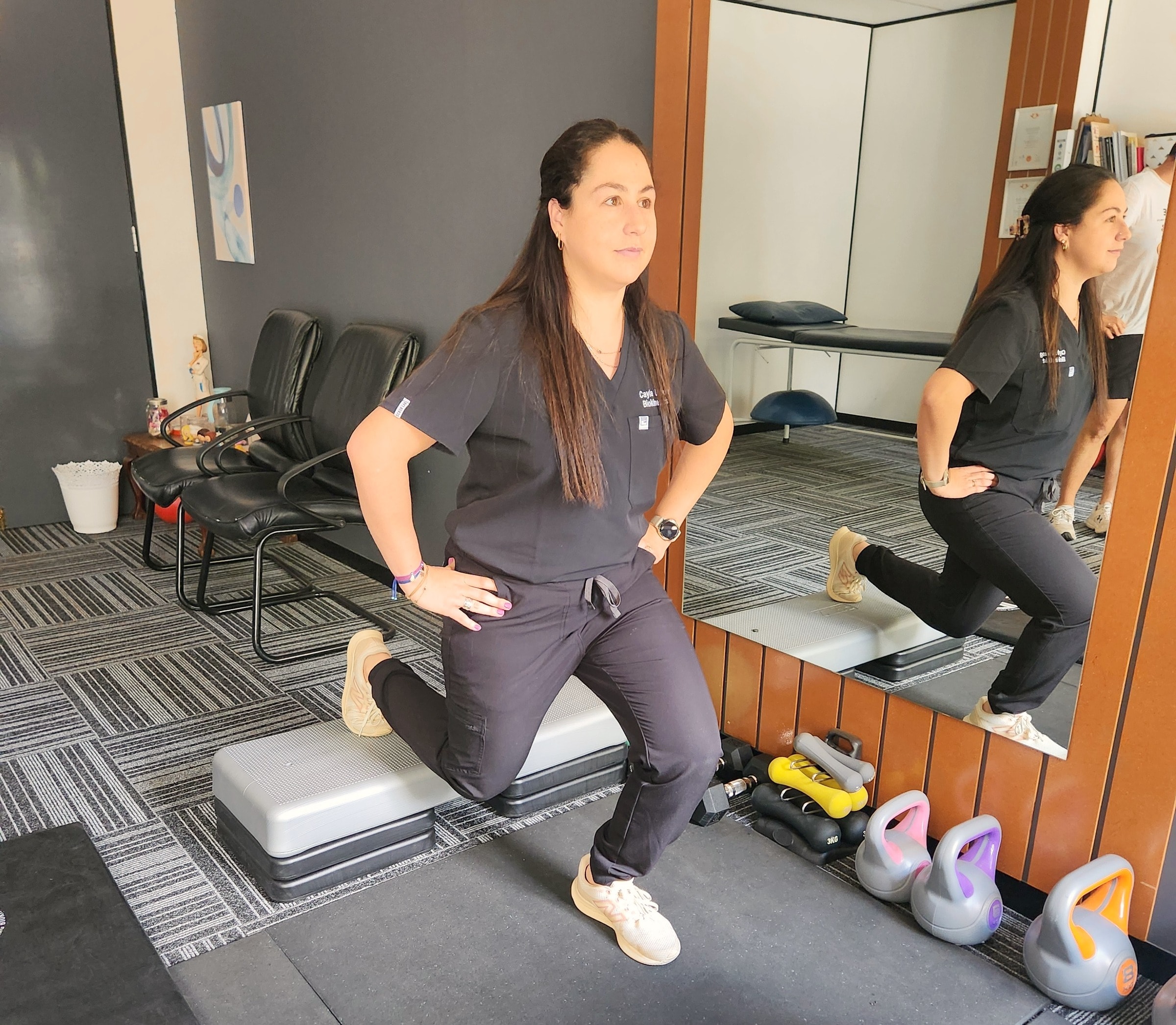 Cayla demonstrating a lunge on a step in front of the mirror