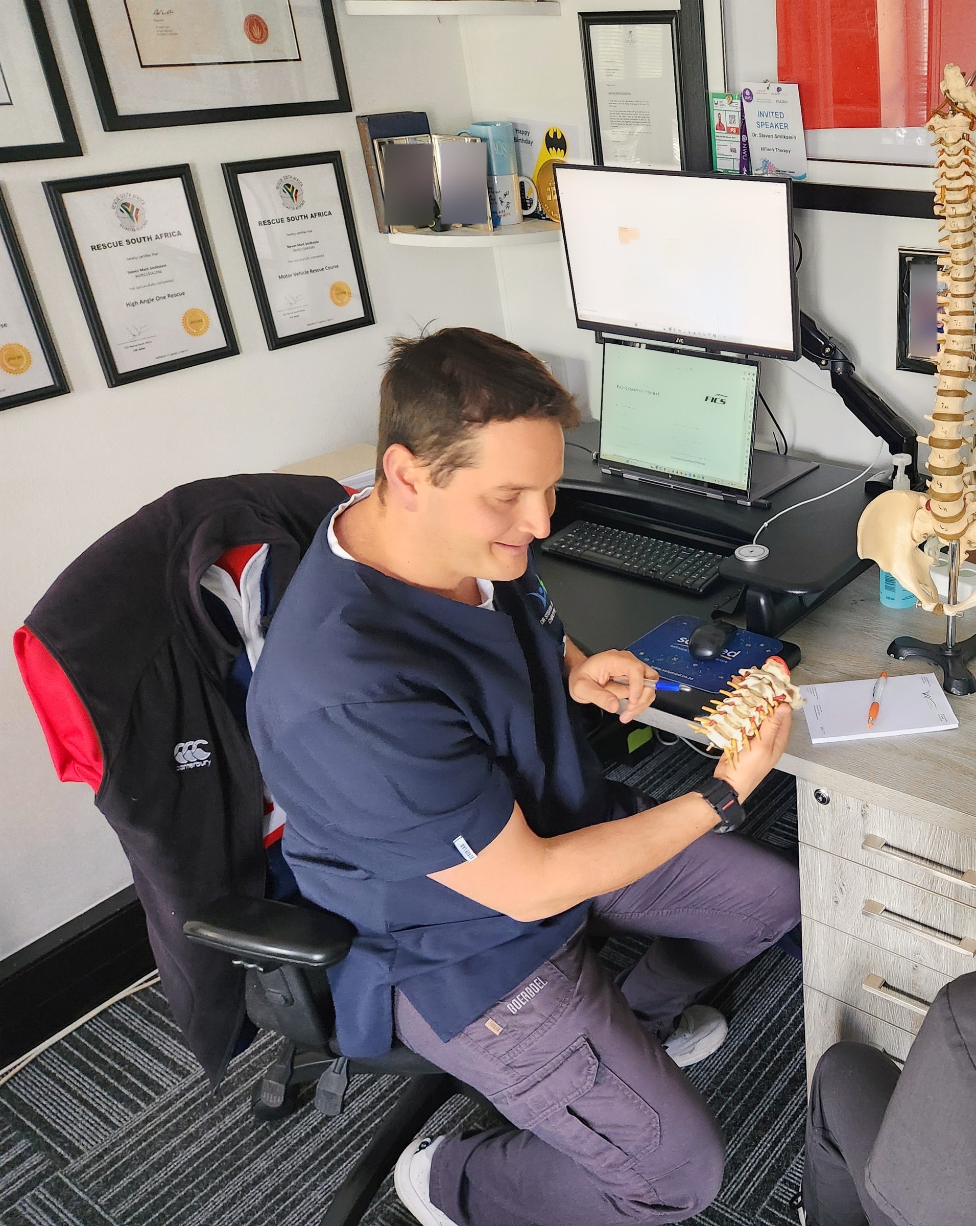 Steven at his desk, explaining with a model of the spine