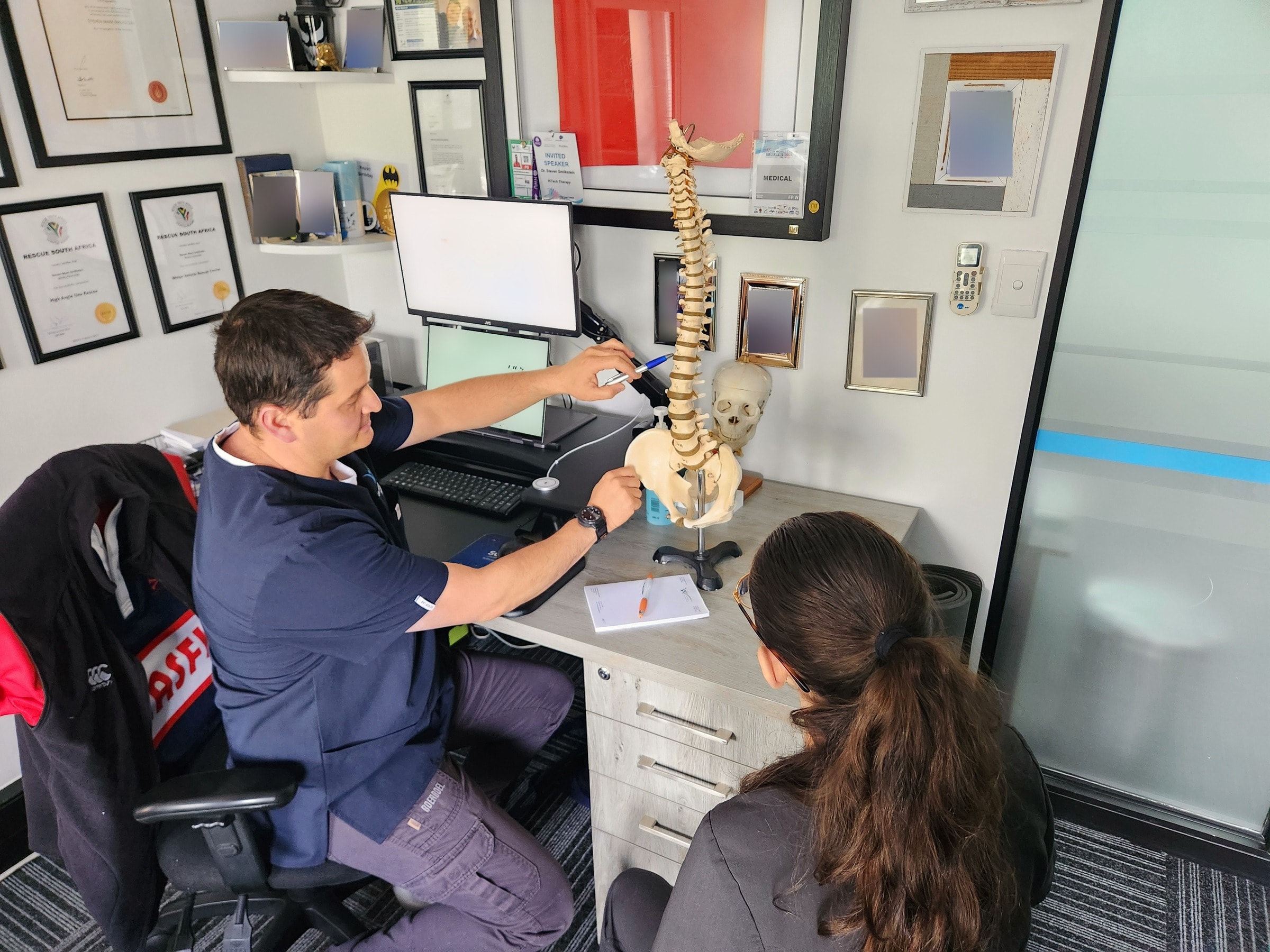 Steven pointing out part of a model spine to a patient